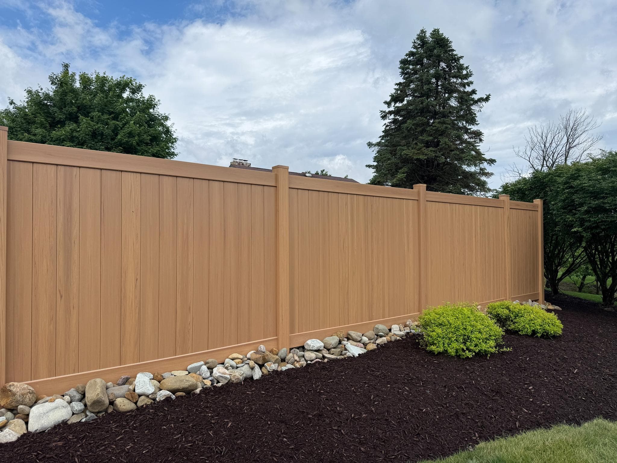 Wood-look vinyl privacy fence with a mulch landscape bed in Pittsburgh